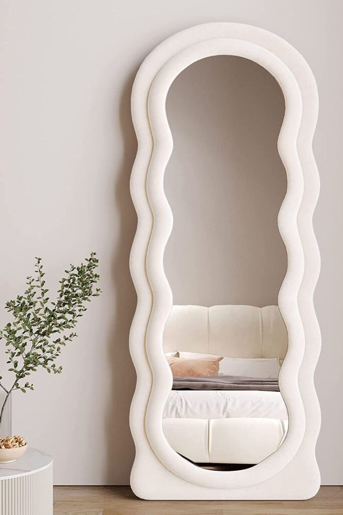 Vintage ornate mirror with intricate floral carvings on a white wall